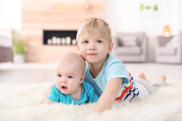 可爱的男孩和他的小妹妹躺在皮草地毯在家里 — 图库照片
