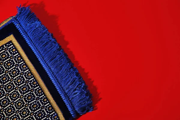 Muslim prayer rug and space for text on color background, top view