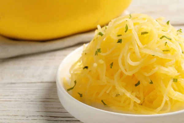 Plate with cooked spaghetti squash on wooden table