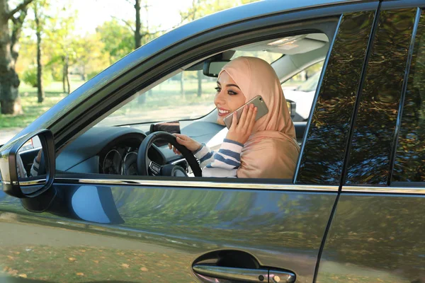 車の運転席で携帯電話で話しているイスラム教徒の女性 — ストック写真