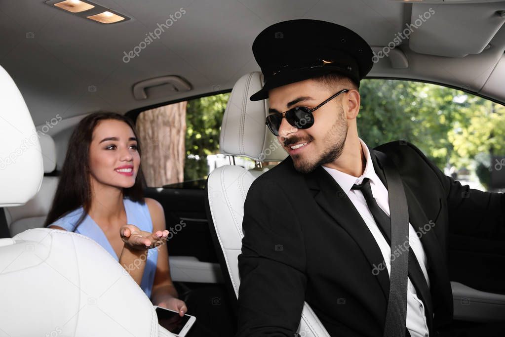 Young businesswoman talking with driver in luxury car