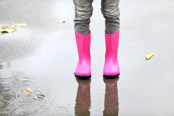 ゴムを身に着けている女の子は 雨の日 足のフォーカスに水たまりに立ってを起動します 秋の散歩 — ストック写真