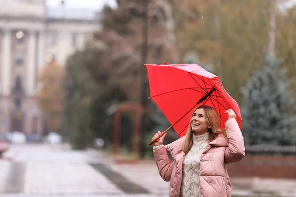 Woman with umbrella in city on autumn rainy day