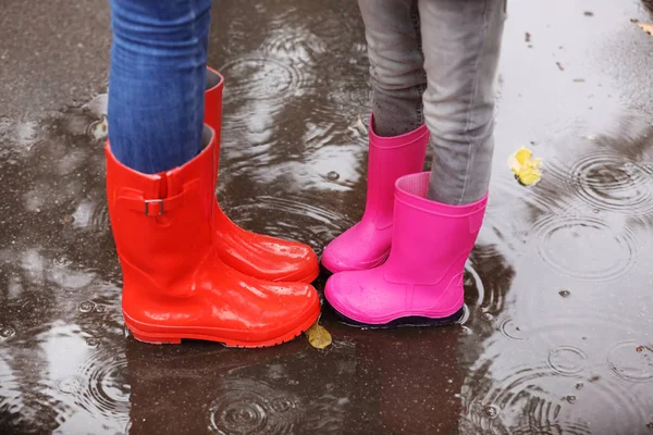 母と娘の身に着けているゴムは 水たまりに雨の日 足の中心に立っているを起動します 秋の散歩 — ストック写真