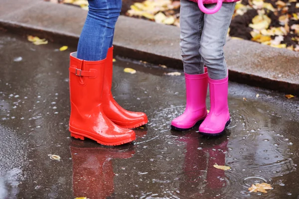 母と娘の身に着けているゴムは 水たまりに雨の日 足の中心に立っているを起動します 秋の散歩 — ストック写真