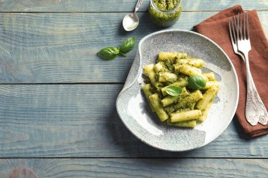 Plaka ile düz yatıyordu bileşimi lezzetli fesleğen pesto makarna ve ahşap masa üzerinde metin için yer