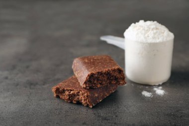 Lezzetli protein bar ve kaşık toz gri masada. Metin için yer