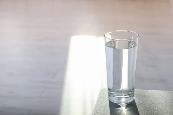 Glass of pure water on table indoors. Space for text