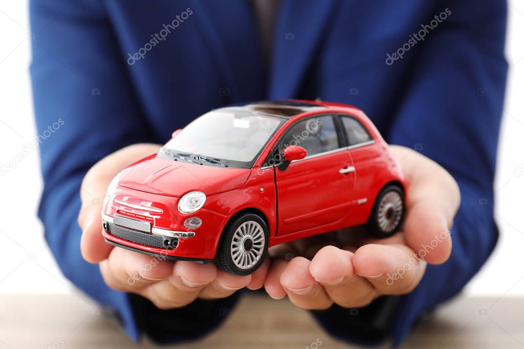 Insurance agent holding toy car over table, focus on hands