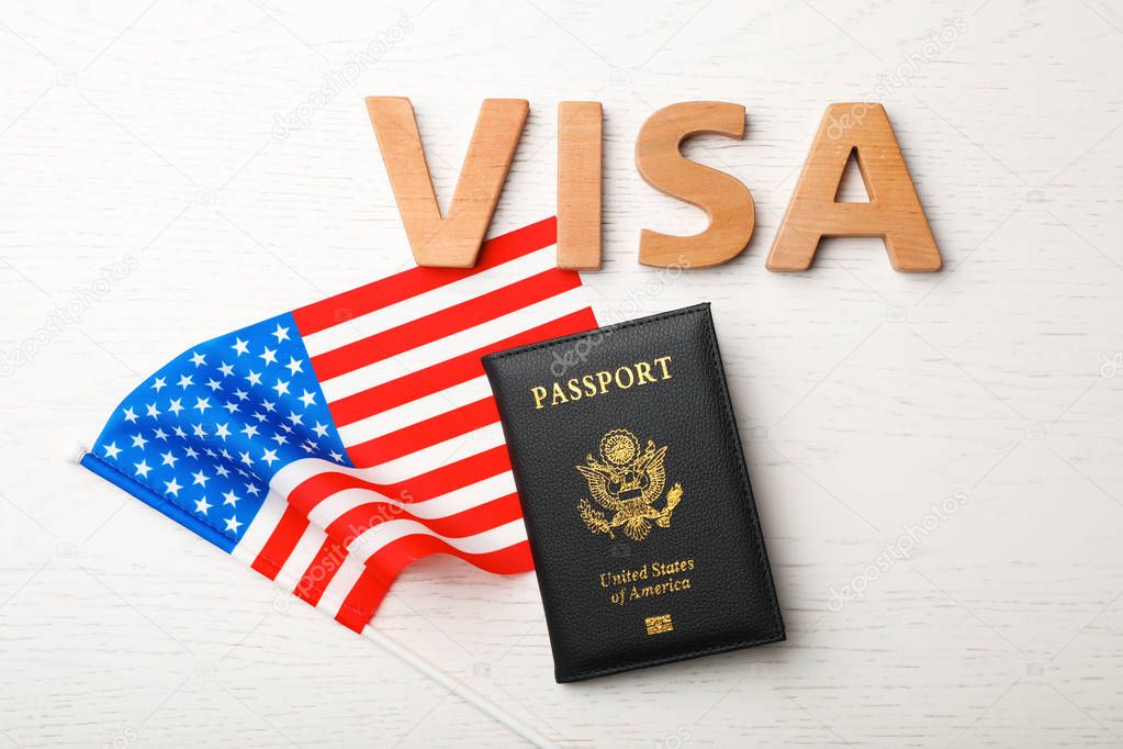 Flat lay composition with flag of USA, passport and word VISA on wooden background