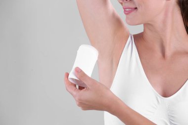 Deodorant gri arka plan üzerinde closeup kullanan genç kadın. Metin için yer