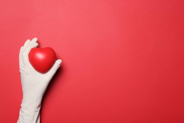 Medikal eldiven renk arka planda, üstten görünüm kalp tutan doktor. Metin için yer