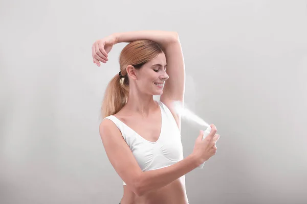 Giovane Donna Utilizzando Deodorante Sfondo Grigio — Foto Stock