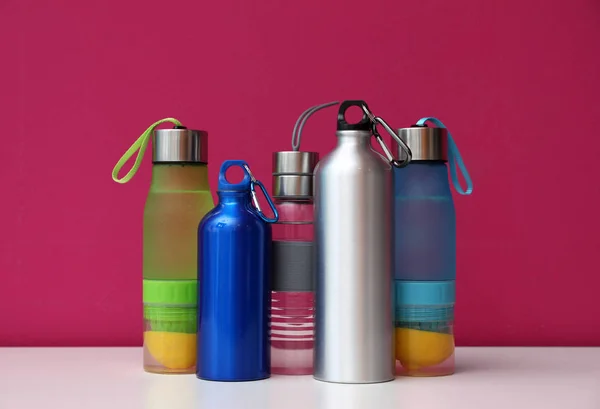 Different water bottles for sports on color background