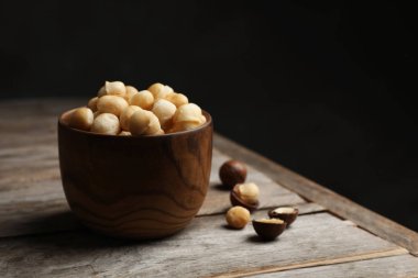 Bir kase koyu arka plan karşı masada organik Macadamia fıstığı kabuklu. Metin için yer