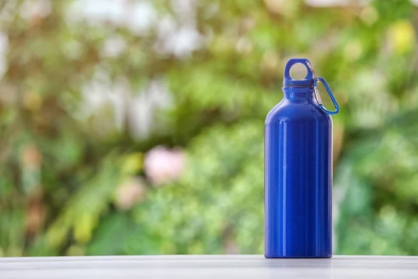 Sports water bottle on table against blurred background. Space for text