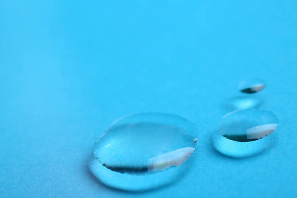 Pure water drops on color background, closeup. Space for text