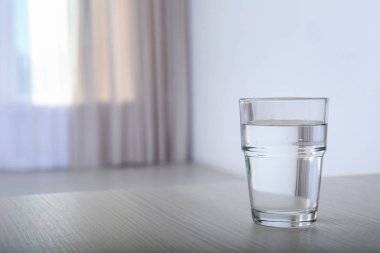 Bardak su tablo arka plan bulanık karşı. Metin için yer