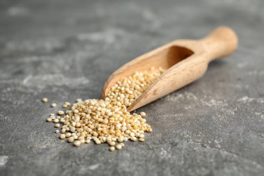 Gri arka plan üzerinde beyaz quinoa ile kepçe