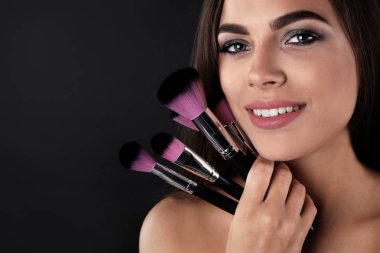 Makyaj ile güzel bir kadın portresi koyu arka plan üzerinde fırçalar. Metin için yer