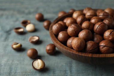 Plaka ile organik Macadamia fındık ve mavi ahşap arka plan üzerinde metin için yer