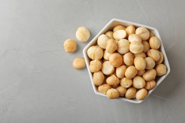 Kabuklu organik Macadamia fıstığı ve gri arka plan, üstten görünüm üzerinde metin için yer ile kase