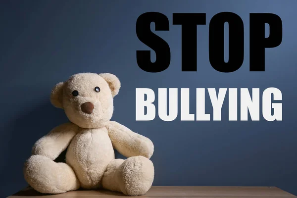 Teddy bear and message STOP BULLYING against color background