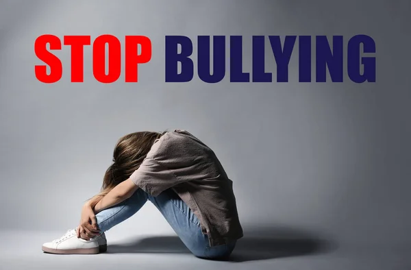 Message STOP BULLYING and sad woman sitting on light background