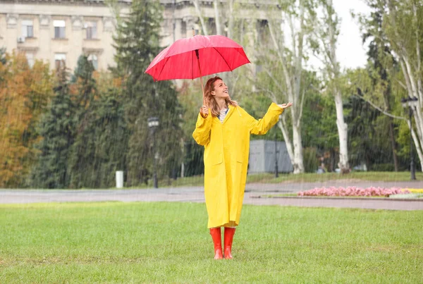 雨の日に公園で赤い傘を持つ幸せな若い女性 — ストック写真