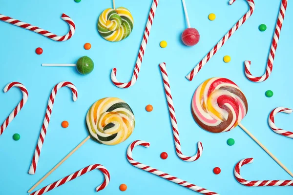 Flat lay composition with tasty candy canes on color background