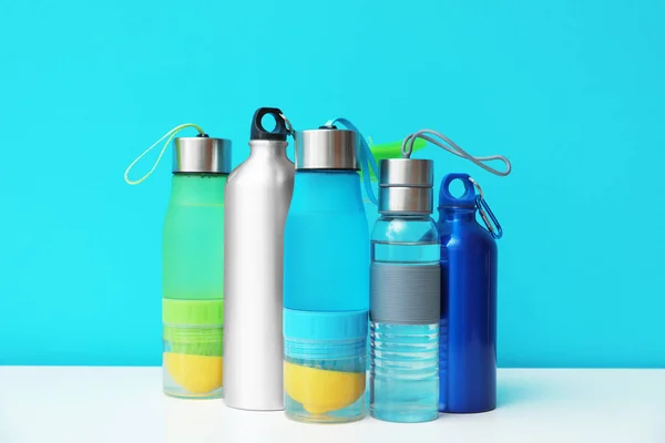 Different water bottles for sports on color background