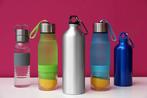 Different water bottles for sports on color background