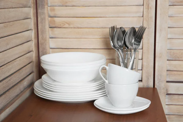 Set of clean dishes and cutlery on table in kitchen