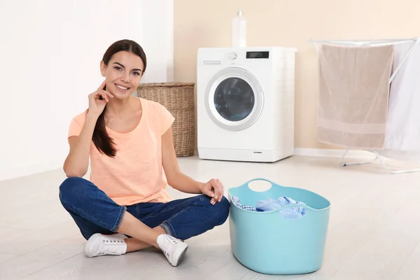 洗濯機の近くに洗濯籠を持つ若い女性 — ストック写真