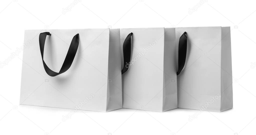 Paper shopping bags with ribbon handles on white background. Mockup for design