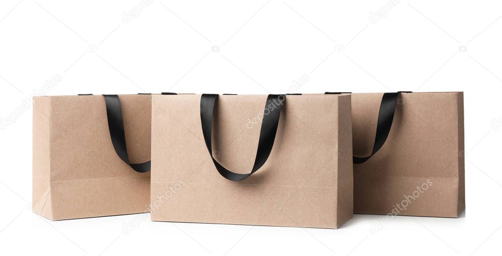 Paper shopping bags with ribbon handles on white background. Mockup for design