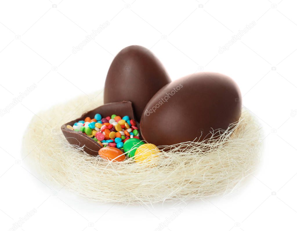 Chocolate Easter eggs in decorative nest on white background
