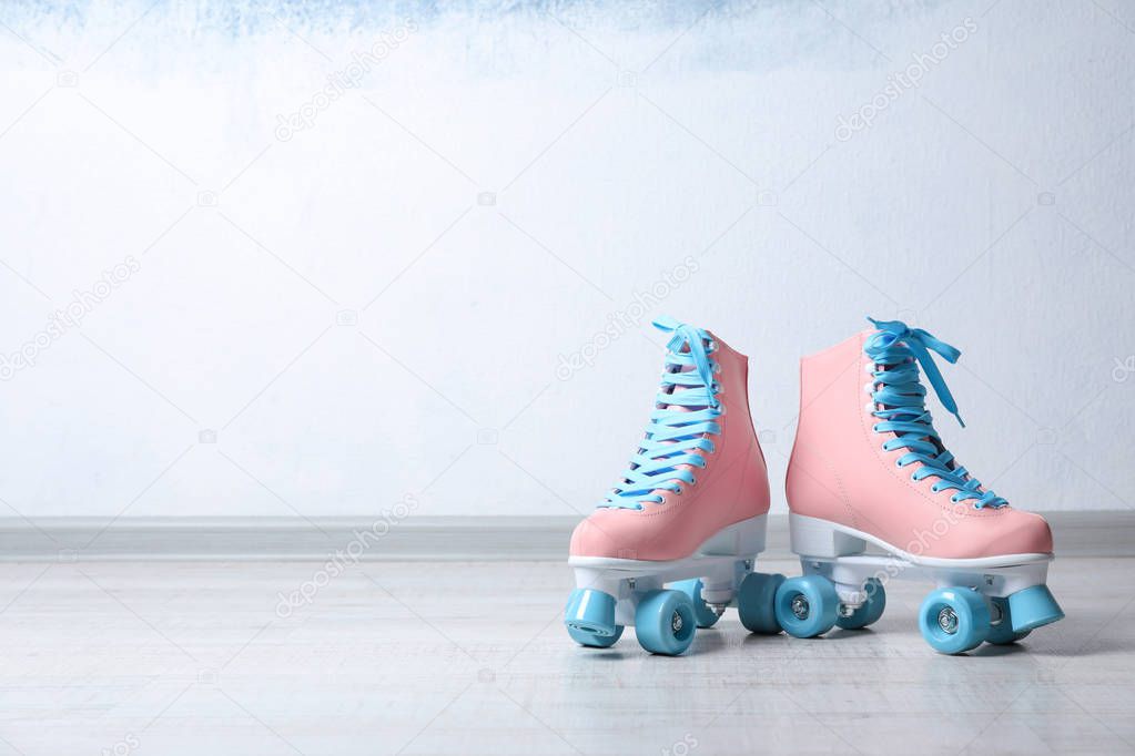 Vintage roller skates on floor near color wall. Space for text