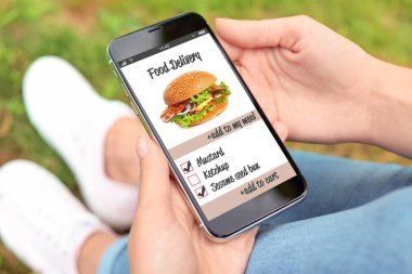 Smartphone-e doğru sipariş gıda teslim açık havada kullanan kadın