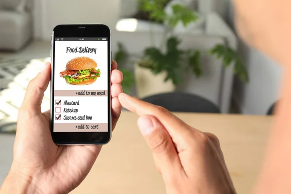 Man using smartphone to order food delivery at home