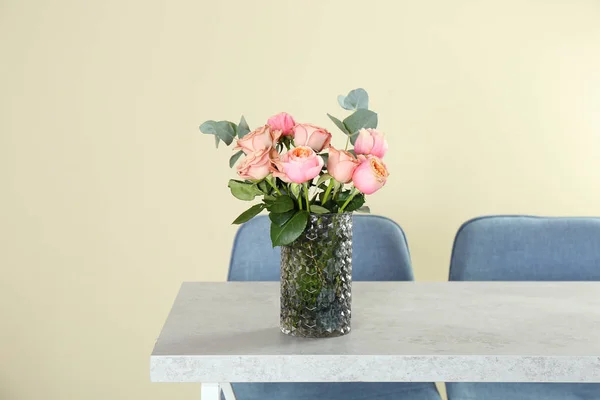 Vase with beautiful flowers as element of interior design on table in room. Space for text