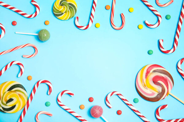 Flat lay composition with tasty candy canes and space for text on color background