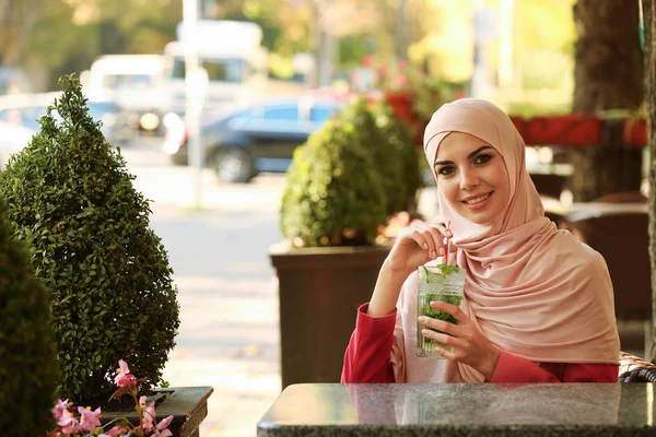 Muslim woman with cocktail in outdoor cafe