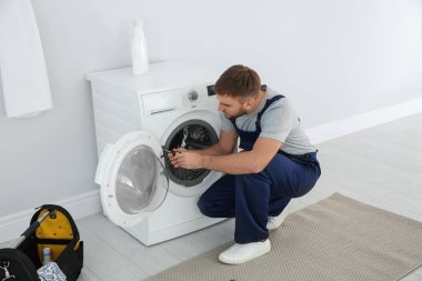 Genç tesisatçı banyoda çamaşır makinesi tamir