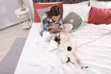 Güzel kadın köpeğini evde yatakta ile oynarken