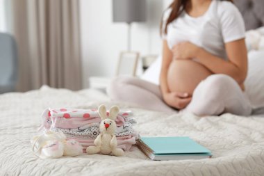 Annelik hastane ve arka plan üzerinde hamile kadın için hazırlanan bebek giysileri