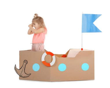 Sevimli küçük kız beyaz zemin üzerine karton gemi ile oynarken