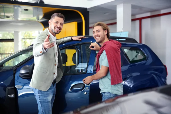 Salesman with customer in modern car dealership