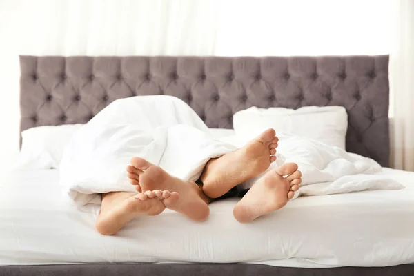 足のクローズ アップのベッドの上の毛布の下に抱きしめること同性カップル — ストック写真