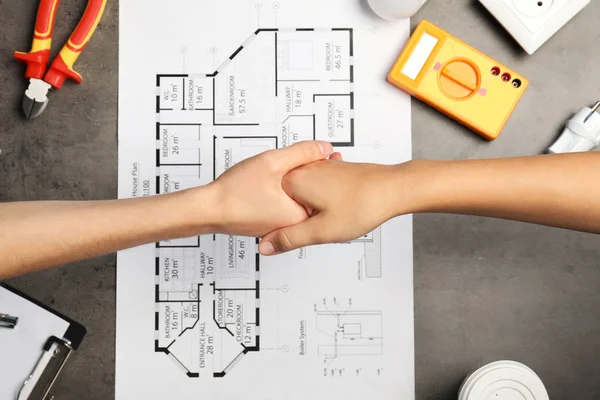 Eletricista Cliente Apertando Mãos Sobre Mesa Com Plano Casa — Fotografia de Stock